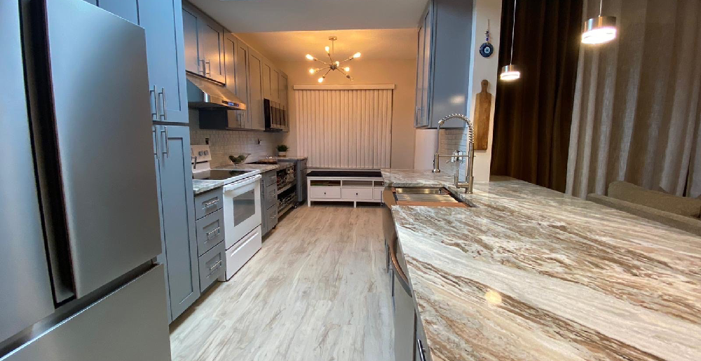 Kitchen remodeling project with custom cabinets waterfall countertop and modern lighting