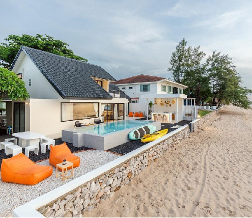 Beachfront home with pool, outdoor seating, and coastal living space near the shoreline