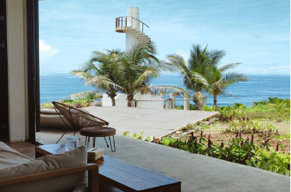 Waterfront home addition with open living space, sliding glass doors, patio, and ocean view
