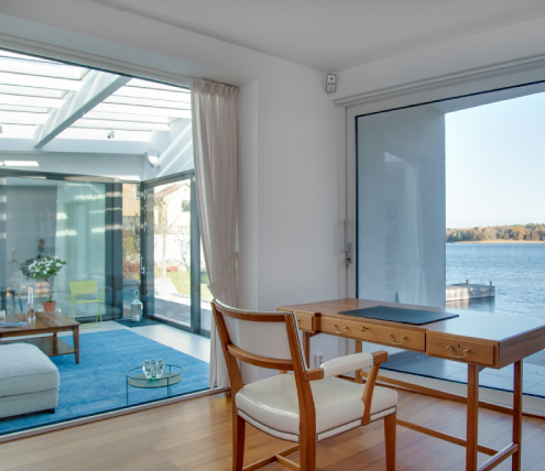 Waterfront home office with large windows, natural light, and a direct water view