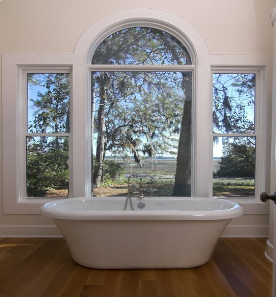 Freestanding bathtub positioned in front of an arched window as part of a custom bathroom remodeling project