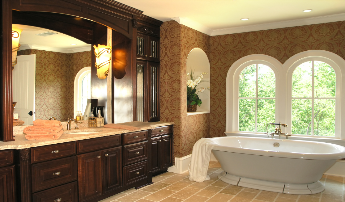 Luxury bathroom remodel featuring a dark wood vanity, large mirror, freestanding bathtub, and arched windows.
