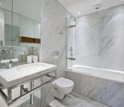 Modern marble bathroom remodel featuring a glass-enclosed tub shower combination, floating toilet, and contemporary vanity.