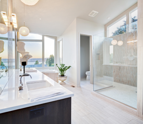 Modern bathroom remodel with a glass walk-in shower, spacious vanity countertop, and large windows providing natural light.